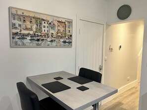 Enjoy a meal at the dining table with two chairs, surrounded by a beautiful European-inspired painting and a stylish door.