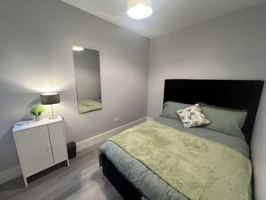Cozy retreat with a neatly made bed, bedside table, and potted plant.