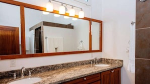 Un baño con dos lavamanos, un espejo grande y una zona de ducha.