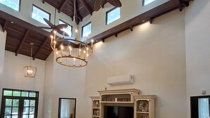 A spacious living room with a large white sofa, a television, and a ceiling fan.