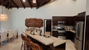 A modern kitchen with dark wooden cabinets, stainless steel appliances, and a central island with bar stools.