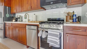 A kitchen with wooden cabinets, stainless steel appliances, and a tiled backsplash.