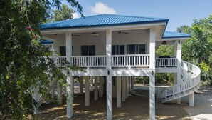 A two-story house with a blue roof, white exterior, and a covered porch with a white railing.
