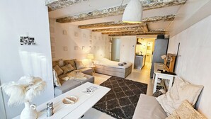 Una sala de estar acogedora con un sofá, una mesita de centro y una lámpara. Se ve un área de cocina al fondo.