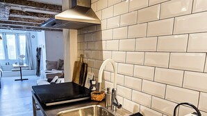 Una cocina moderna con encimera de acero inoxidable, un lavaplatos integrado y una campana extractora.