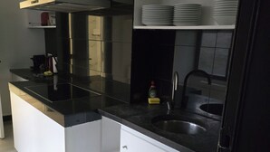 Una cocina moderna con encimera negra, electrodomésticos de acero inoxidable y armarios blancos.
