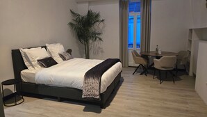 A modern bedroom with a large bed, a small round table, and a chair.