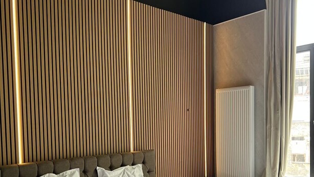 Una habitación de hotel moderna con una cama grande, una bañera redonda y un panel de pared de madera.