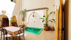 A courtyard with a pool, seating area, and potted plants.
