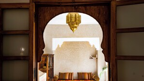 A room with a wooden-framed arched doorway, a sofa with striped cushions, and a hanging lamp.