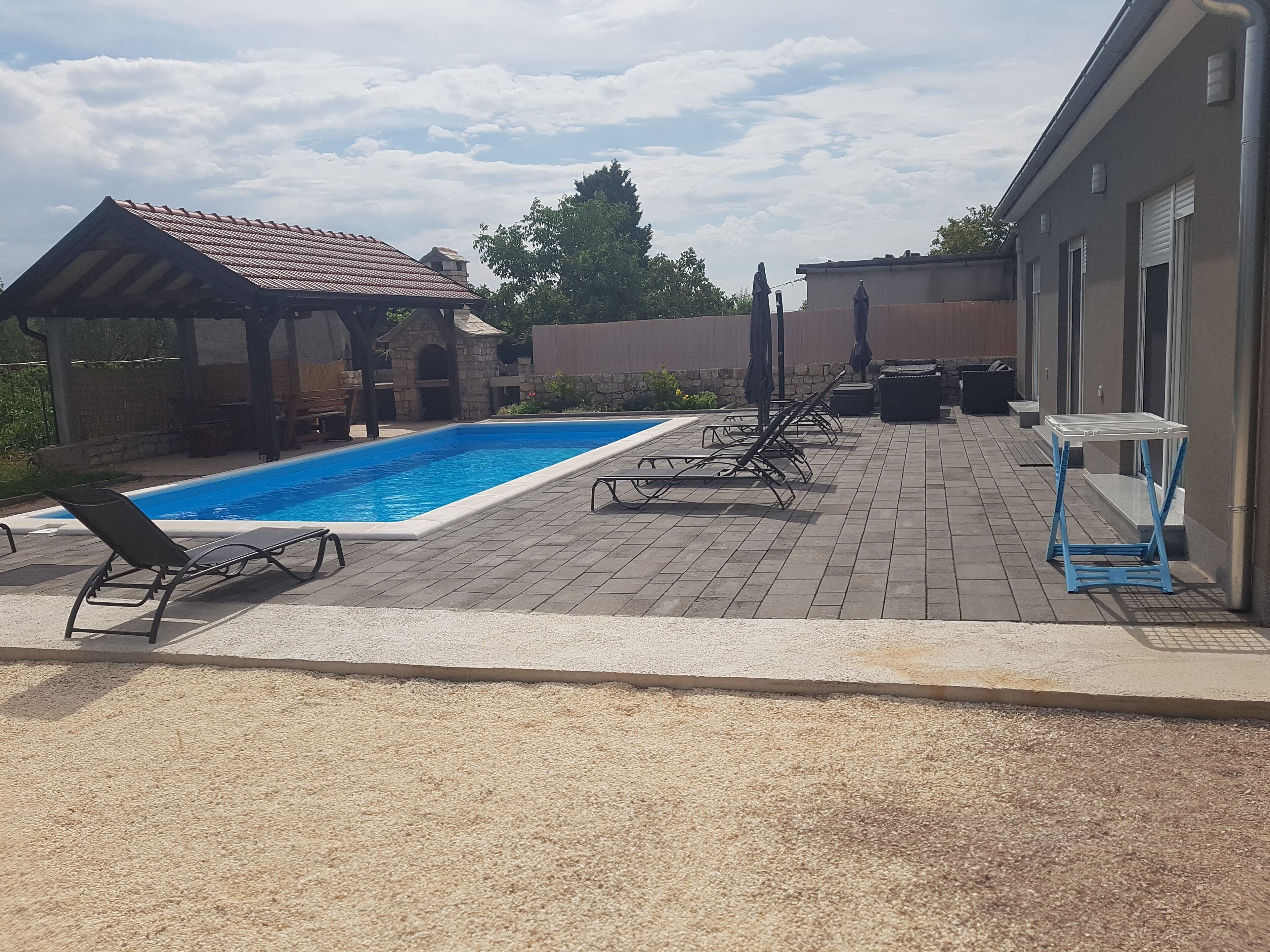 Um quintal com piscina, espreguiçadeiras e um pergolado.