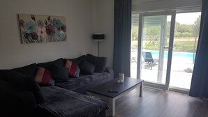 A modern living room with a sectional sofa, a coffee table, and a painting on the wall.