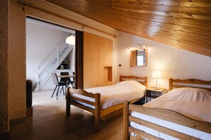 A cozy bedroom with two wooden beds, a desk, and a chair.