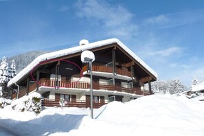 A multi-story chalet with a snow-covered roof and balconies, surrounded by a snowy landscape. - 50m from ski slopes, 3rd floor, view village/mountain, balcony, tv, 76m², La Clusaz (La Clusaz)