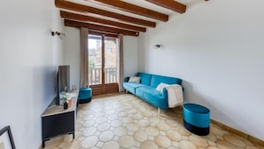 Una habitación con un sofá azul, un mueble de televisión de madera y un suelo con baldosas hexagonales.
