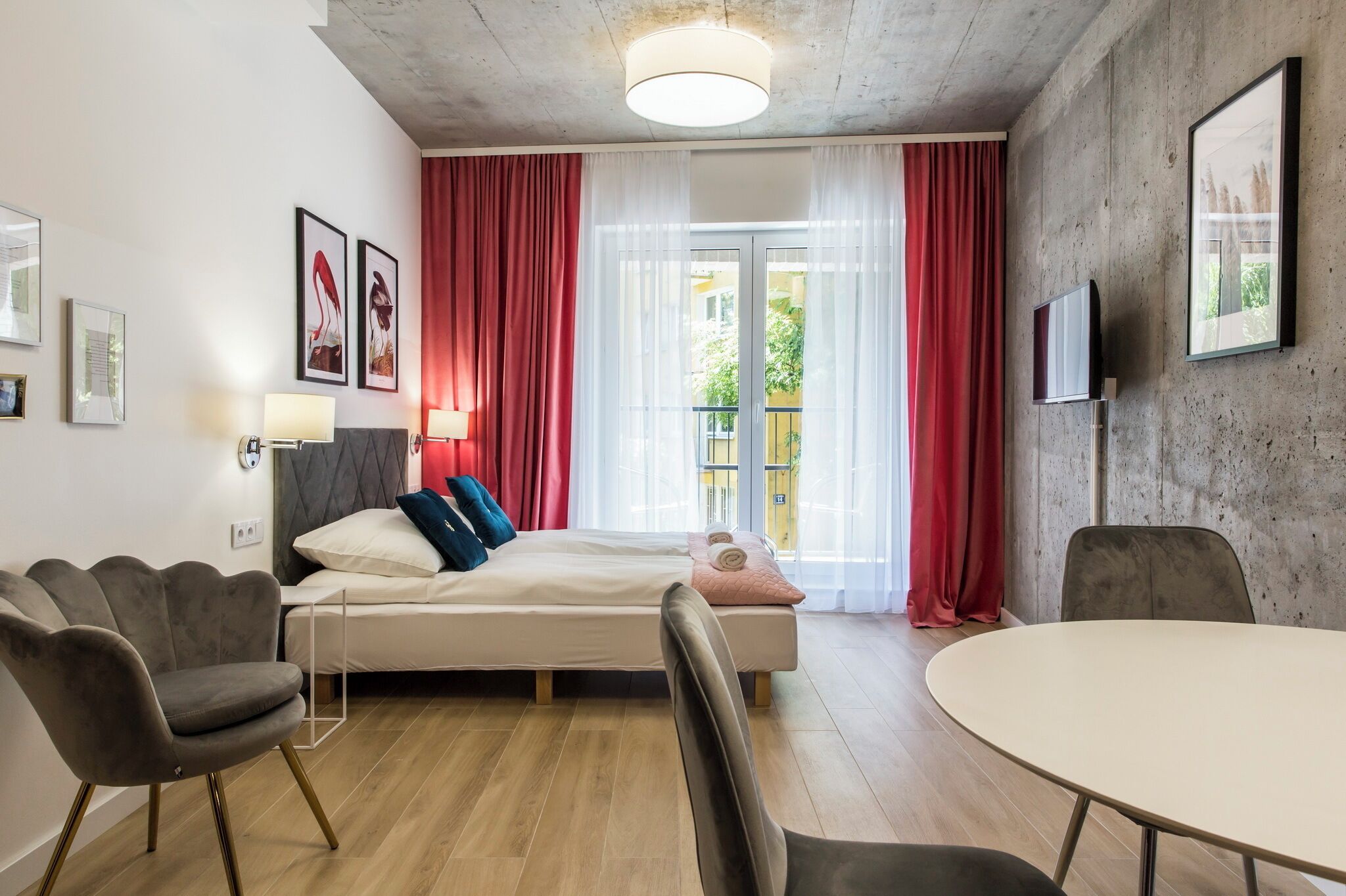 Une chambre d’hôtel moderne équipée d’un lit, de deux fauteuils, d’une table et d’un téléviseur.