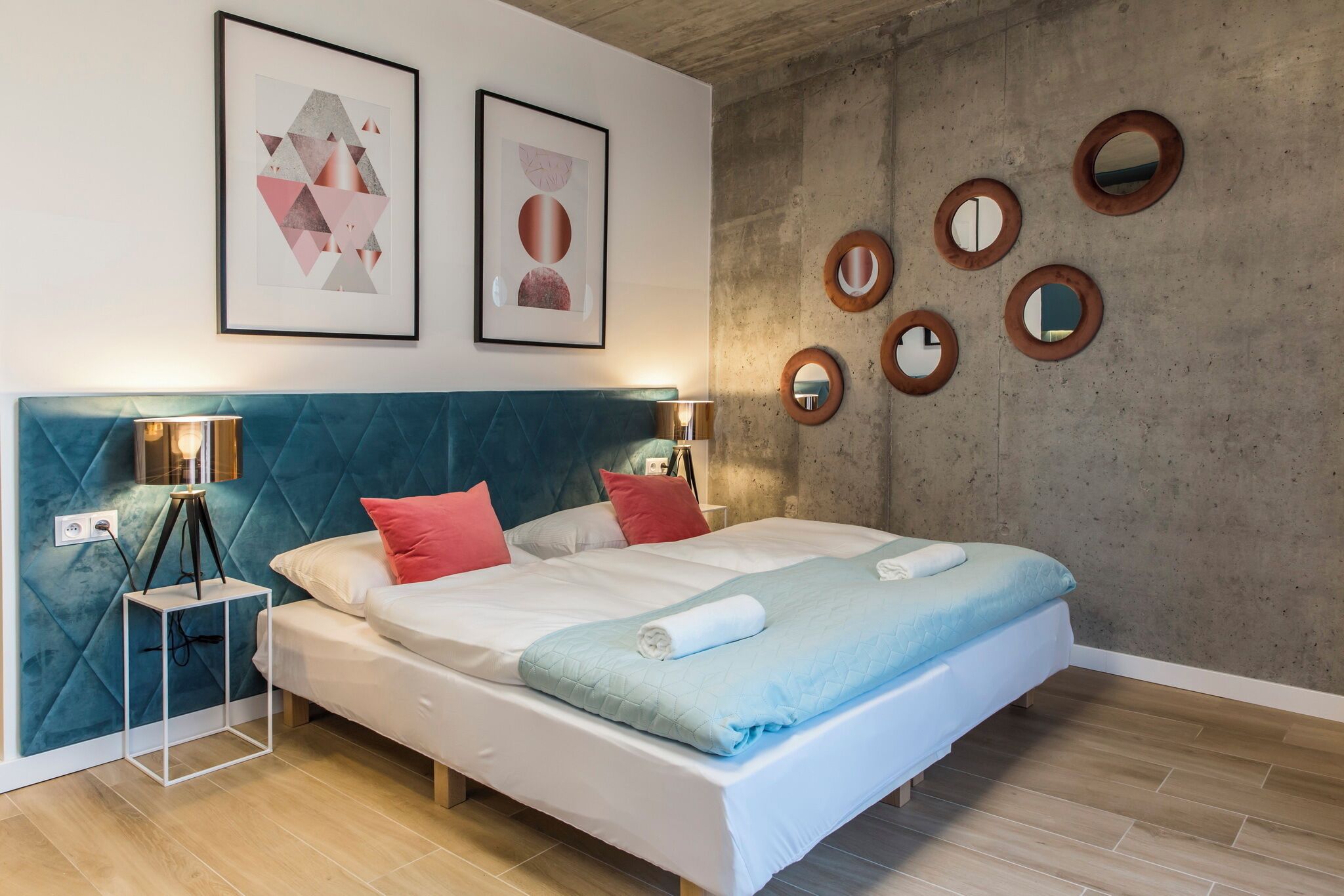 A modern bedroom with a large bed, two bedside lamps, and a wall with circular mirrors.