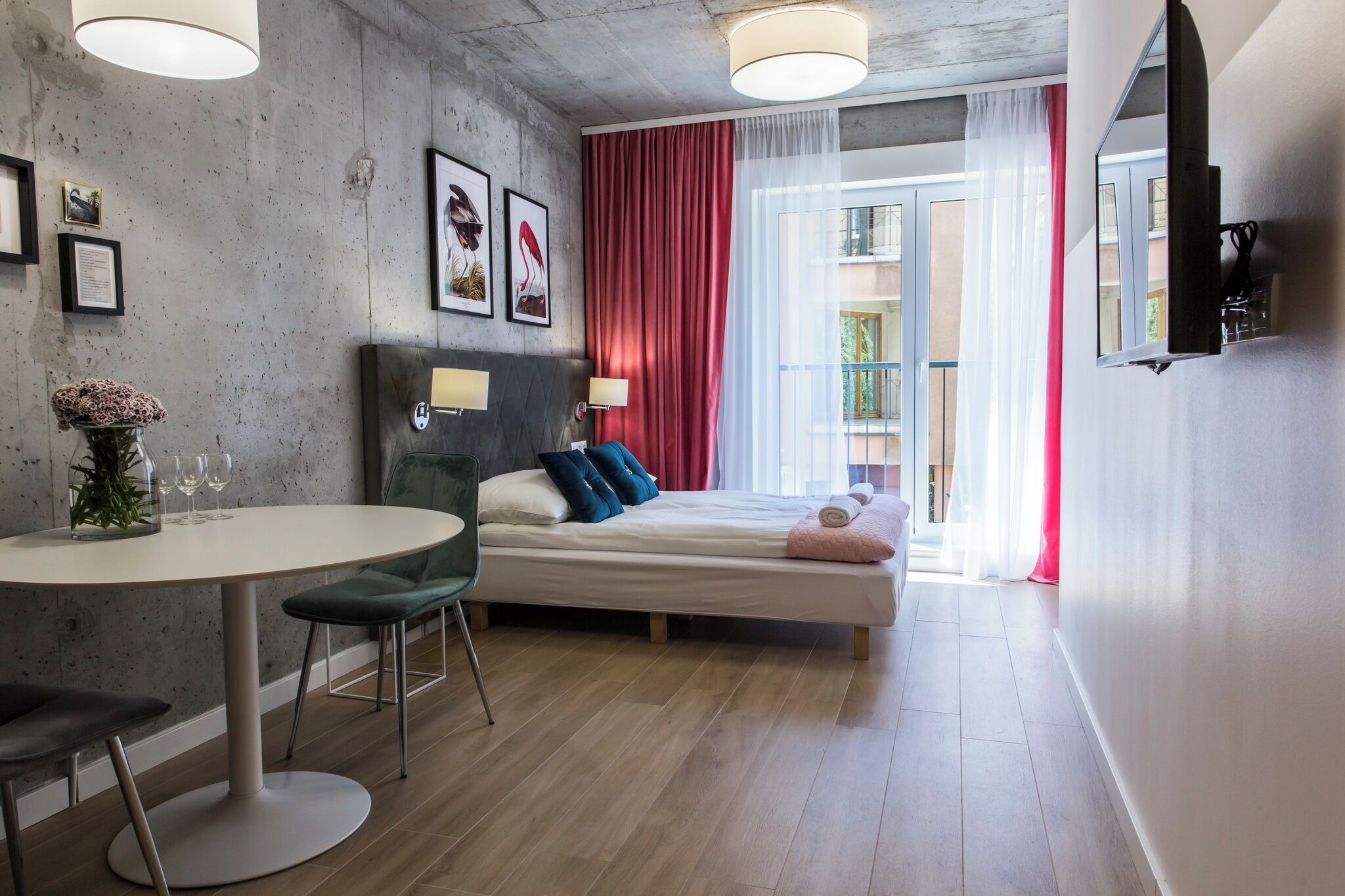 Ein modernes Hotelzimmer mit einem Bett, einem runden Esstisch und einem an der Wand befestigten Fernseher.