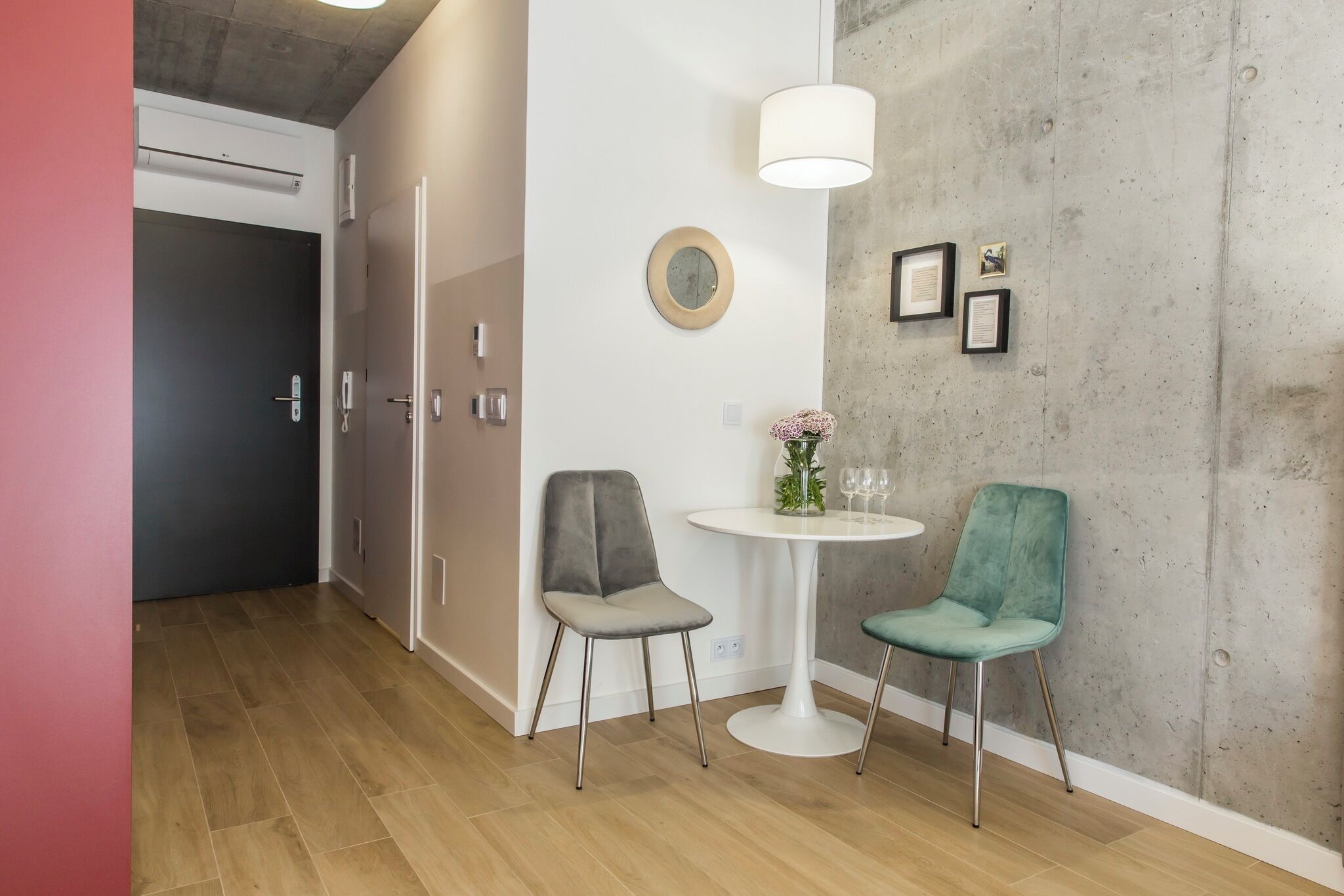 Habitació moderna amb una taula rodona, dues cadires, una làmpada penjada a la paret i quadres emmarcats.