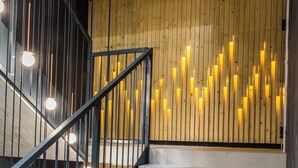 A staircase with a wooden wall and illuminated panels, a metal railing, and a concrete ceiling. - Piedmont House (Kraków)
