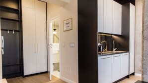 A modern kitchen with white cabinets, a black countertop, and a visible light fixture. - Piedmont House (Kraków)