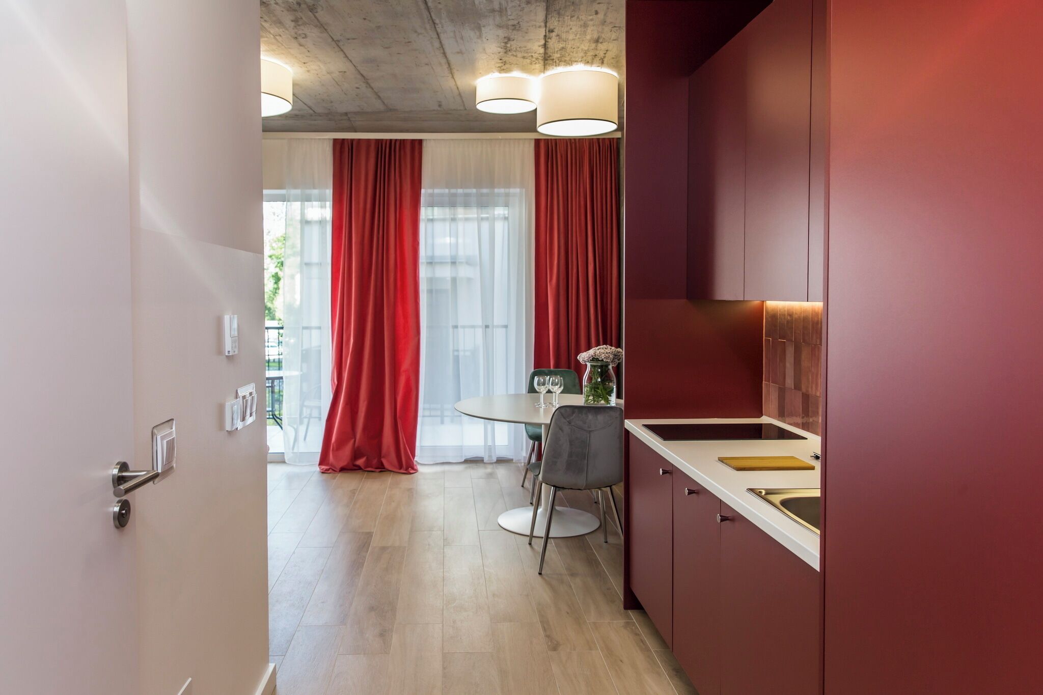 Una cocina moderna con comedor, cortinas rojas y vistas al exterior.
