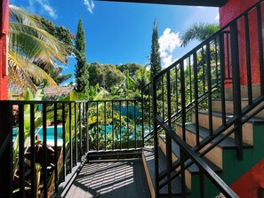 A staircase leading to a pool surrounded by lush greenery and a clear blue sky.