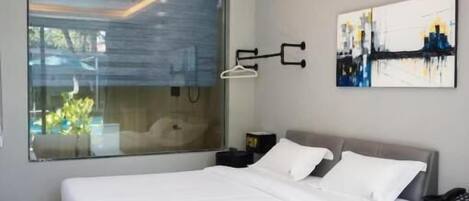 A modern bedroom with a large bed, a glass wall, and a cityscape view.