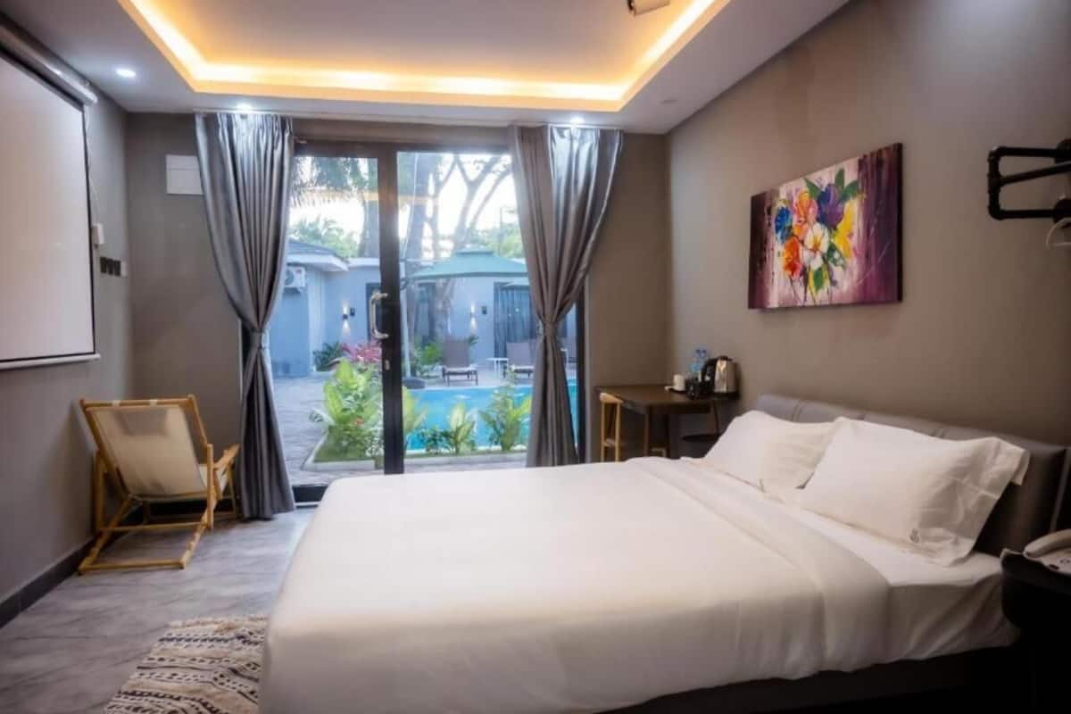 Ein Hotelzimmer mit einem großen Bett, einem Schreibtisch, einem Stuhl und Blick auf einen Swimmingpool.