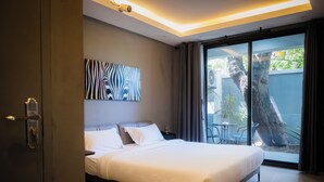 Een moderne hotelkamer met een groot bed, een beveiligingscamera aan het plafond, uitzicht op de omgeving en een groot raam met gordijnen.