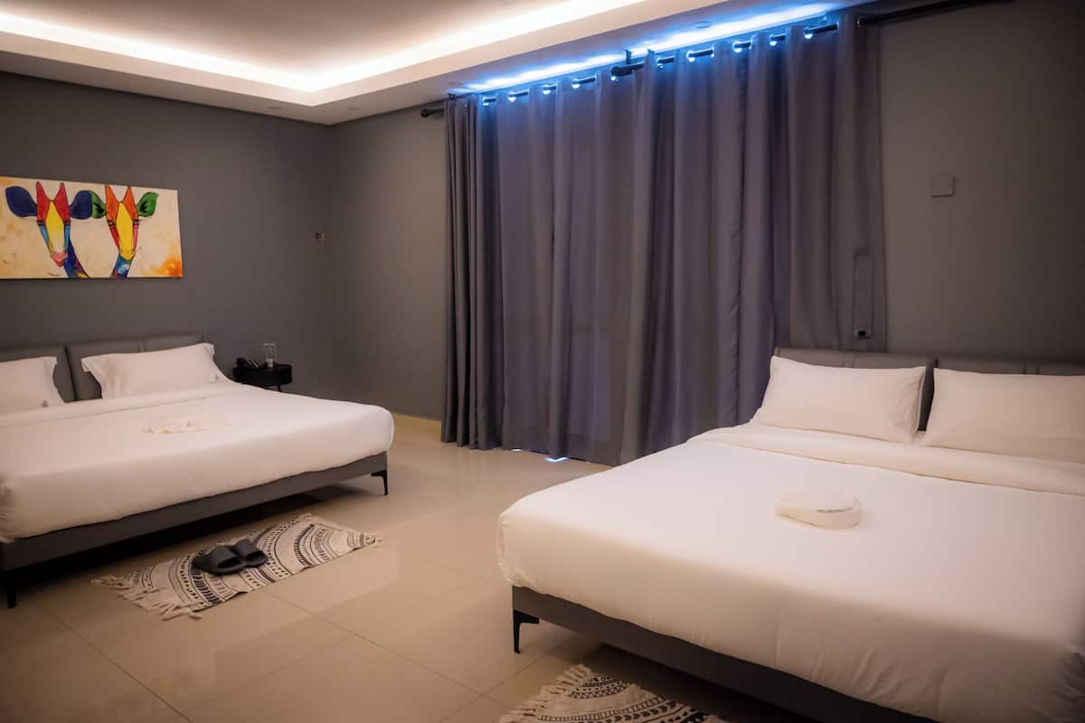 Ein modernes Hotelzimmer mit zwei Betten, einem großen Gemälde an der Wand und Blick auf die Stadt durch das Fenster.