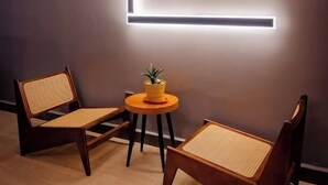 Een moderne kamer met twee houten stoelen, een klein rond tafeltje en een potplant.
