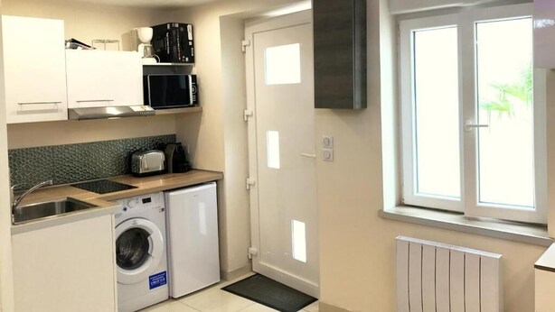 Une cuisine compacte équipée d’un lave-linge, d’un four à micro-ondes et d’un four encastré.