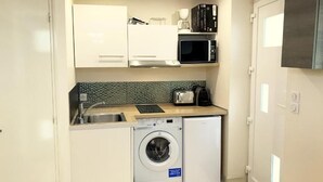 Une cuisine compacte équipée d’un lave-linge, d’un four à micro-ondes et d’un grille-pain.
