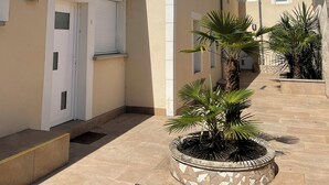 Une ruelle étroite bordée de bâtiments des deux côtés, avec des toits couverts de tuiles, un petit clocher et des plantes en pot.