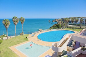 Un complexe hôtelier doté d’une grande piscine, de palmiers et offrant une vue sur l’océan.