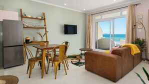 Een moderne woonkamer met een eethoek, een bank, een televisie en uitzicht op de oceaan.