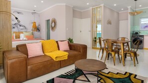 Een moderne woonkamer met een bruine leren bank, een gele plaid en een eetgedeelte met een houten tafel en stoelen.