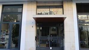 A building entrance with a glass door, a metal gate, and a balcony. - Apartment for groups with free parking  (Sevilla)