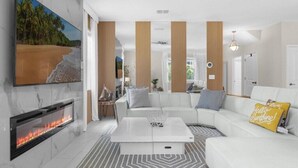 A modern living room with a fireplace, a white sofa, and a coffee table. - EV_9026 - 6 Bed 6 Bath Home with Screened-In Private Pool with Spillover Spa and (Davenport)