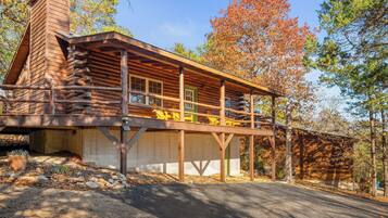 A log cabin with a covered porch and a stone foundation.