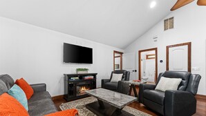 A living room with a fireplace, a flat-screen TV, leather sofas, and a coffee table.