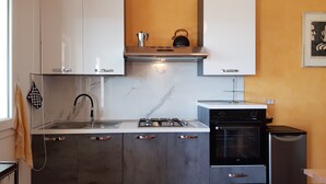 A modern kitchen with white cabinets, a gas stove, a built-in oven, and a dishwasher. - Spacious, quiet apartment close to the beach with magnificent views (Quartu Sant'Elena)