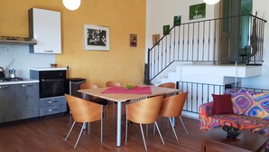 A modern kitchen with a dining area, wooden flooring, and a staircase leading to an upper level. - Spacious, quiet apartment close to the beach with magnificent views (Quartu Sant'Elena)