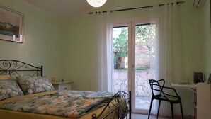 A bedroom with a bed, a desk with a chair, a window, and a door leading to an outdoor area. - Spacious, quiet apartment close to the beach with magnificent views (Quartu Sant'Elena)