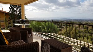 A balcony with wicker furniture and a view of a cityscape. - Spacious, quiet apartment close to the beach with magnificent views (Quartu Sant'Elena)