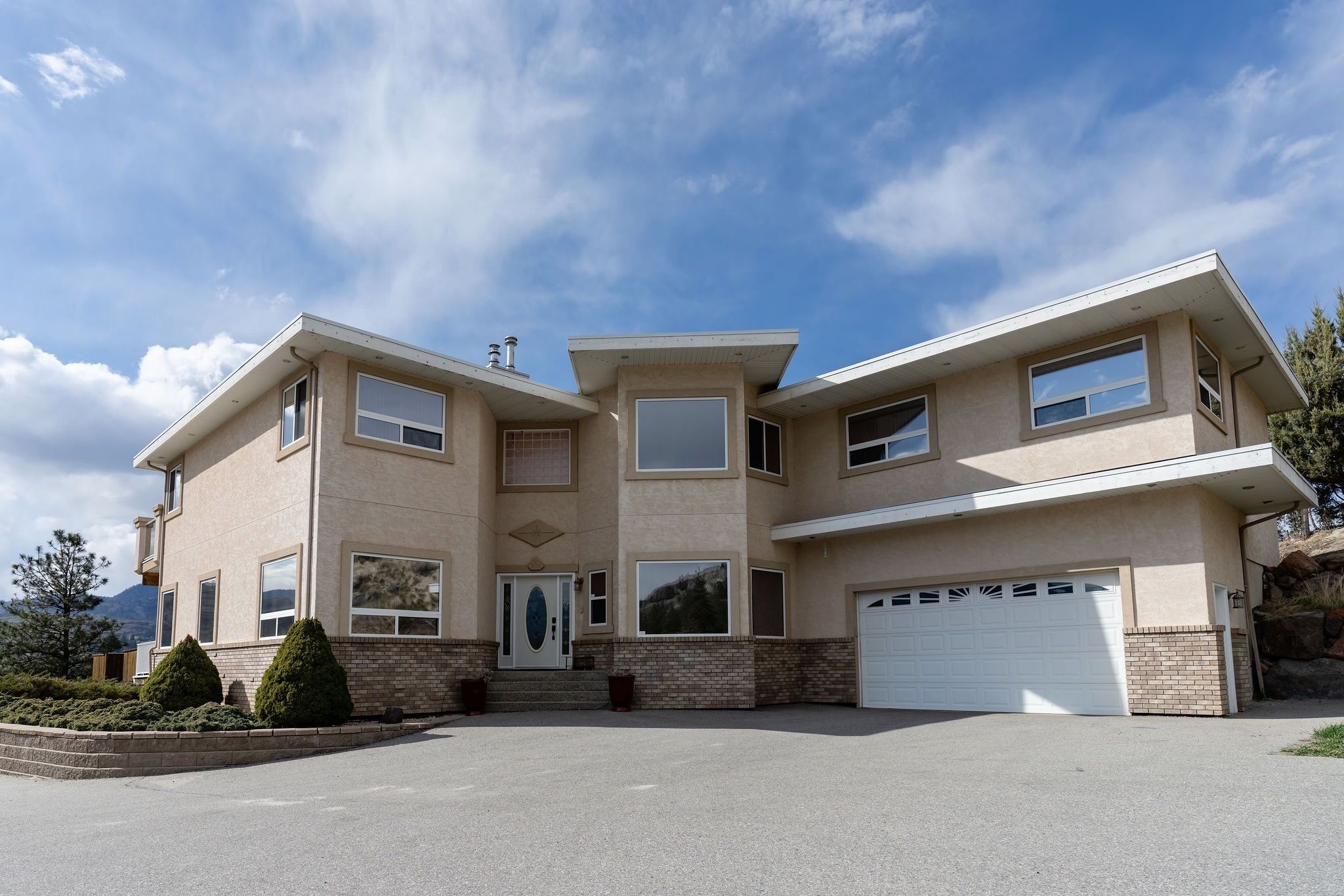Une maison à deux étages avec un garage, une porte d’entrée et une allée.
