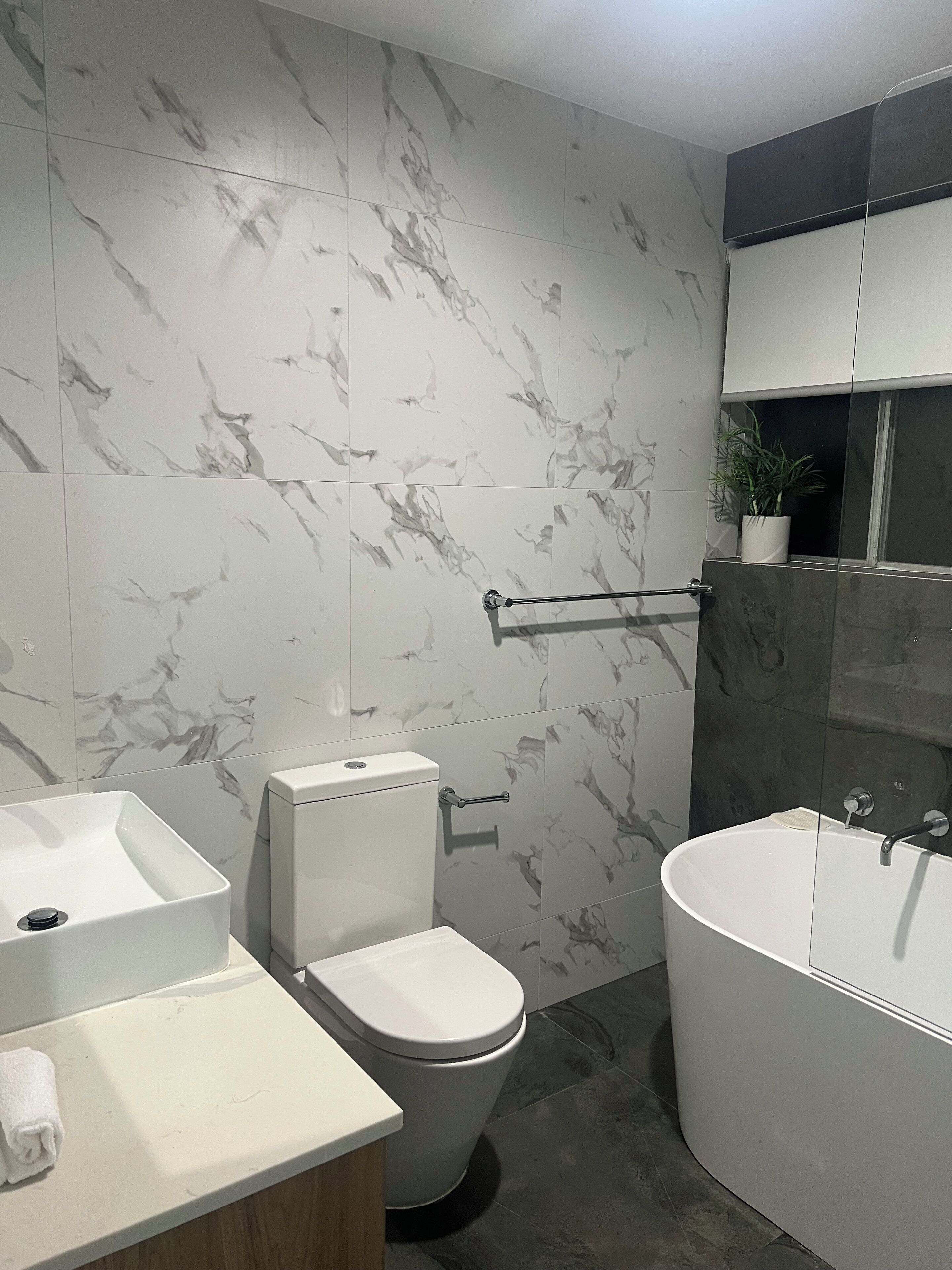Ein modernes Badezimmer mit Toilette, Waschbecken und Badewanne.