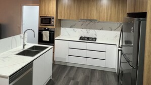 Una cucina moderna con isola centrale, forno integrato, microonde e frigorifero in acciaio inossidabile.