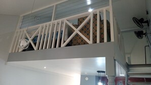 A room with a balcony, a ceiling fan, and a patterned curtain. - Cozy Studio with Loft WiFi and AC in New Kingston (Kingston)